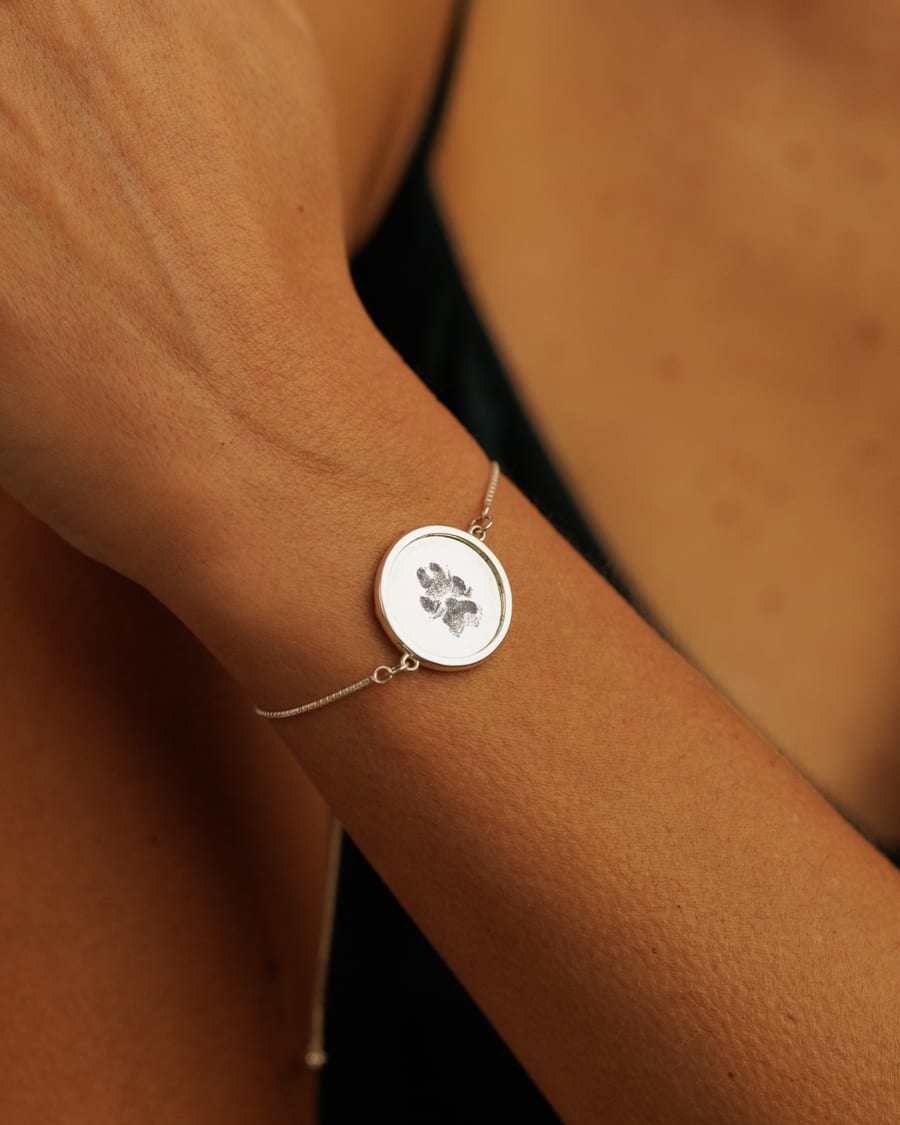 A sterling silver paw print bracelet worn on the wrist